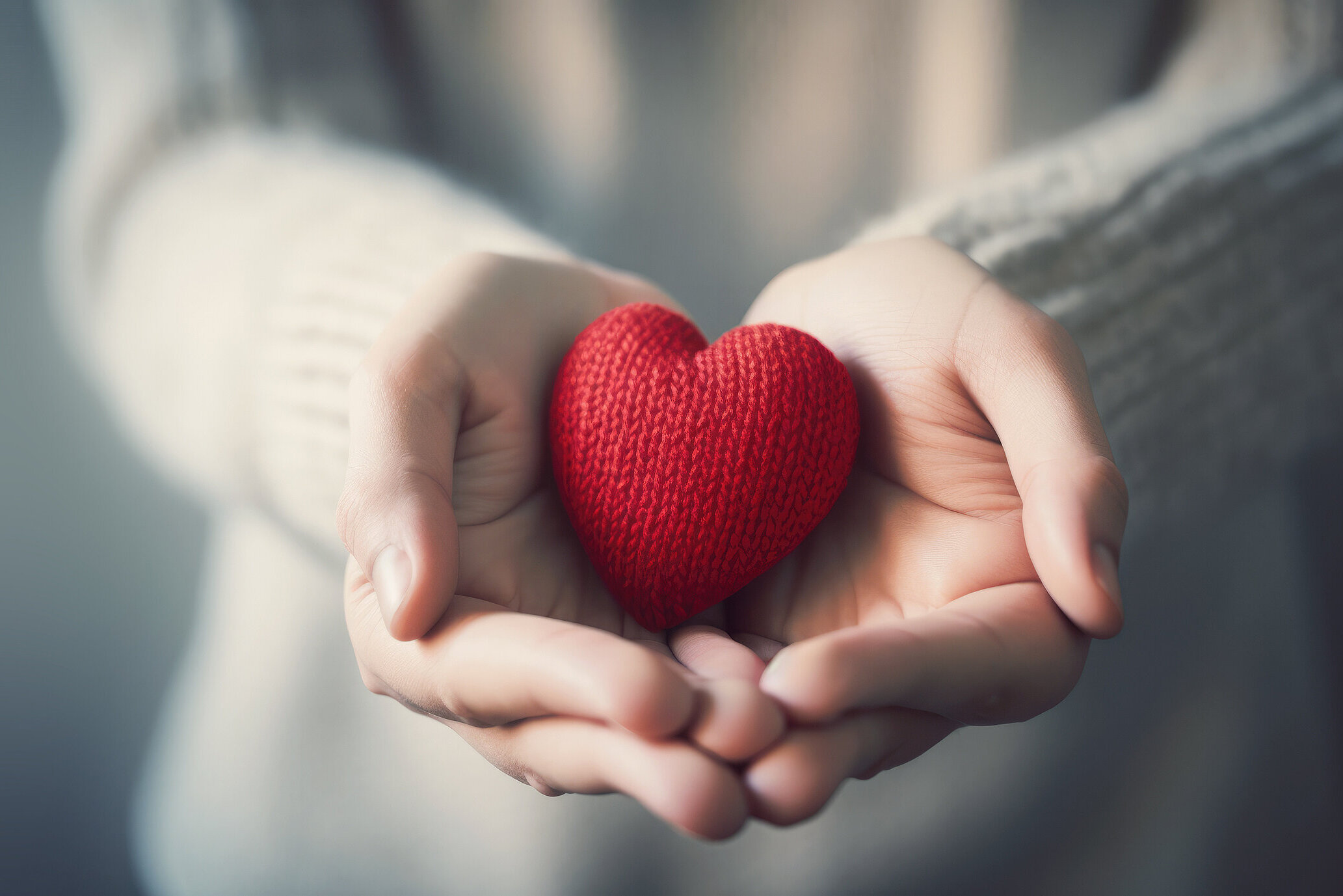 ©iDoPixBox_AdobeStock Titelbild Starseite Hände tragen ein kleines rotes Stoffherz